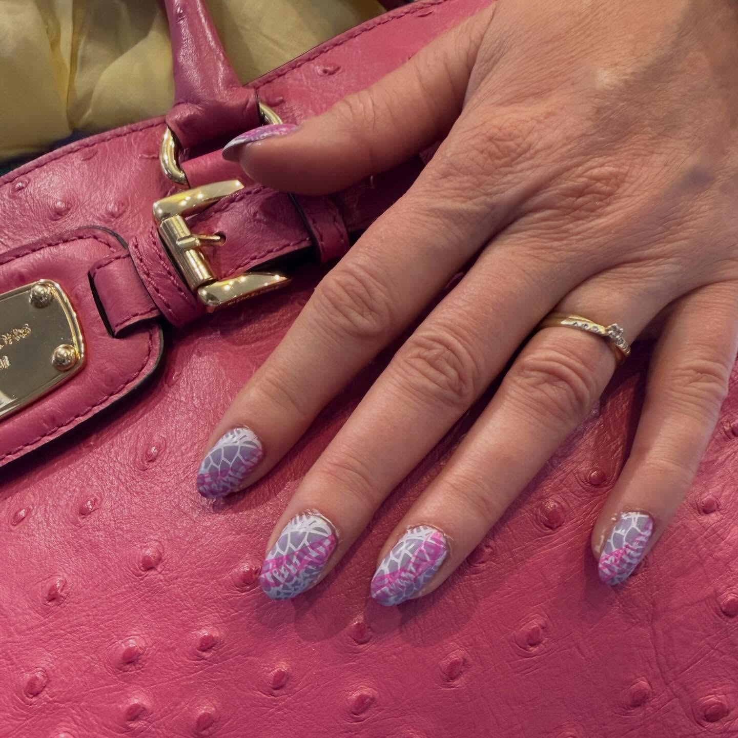 Lila nail art met een spinnenwebpatroon op een roze tas