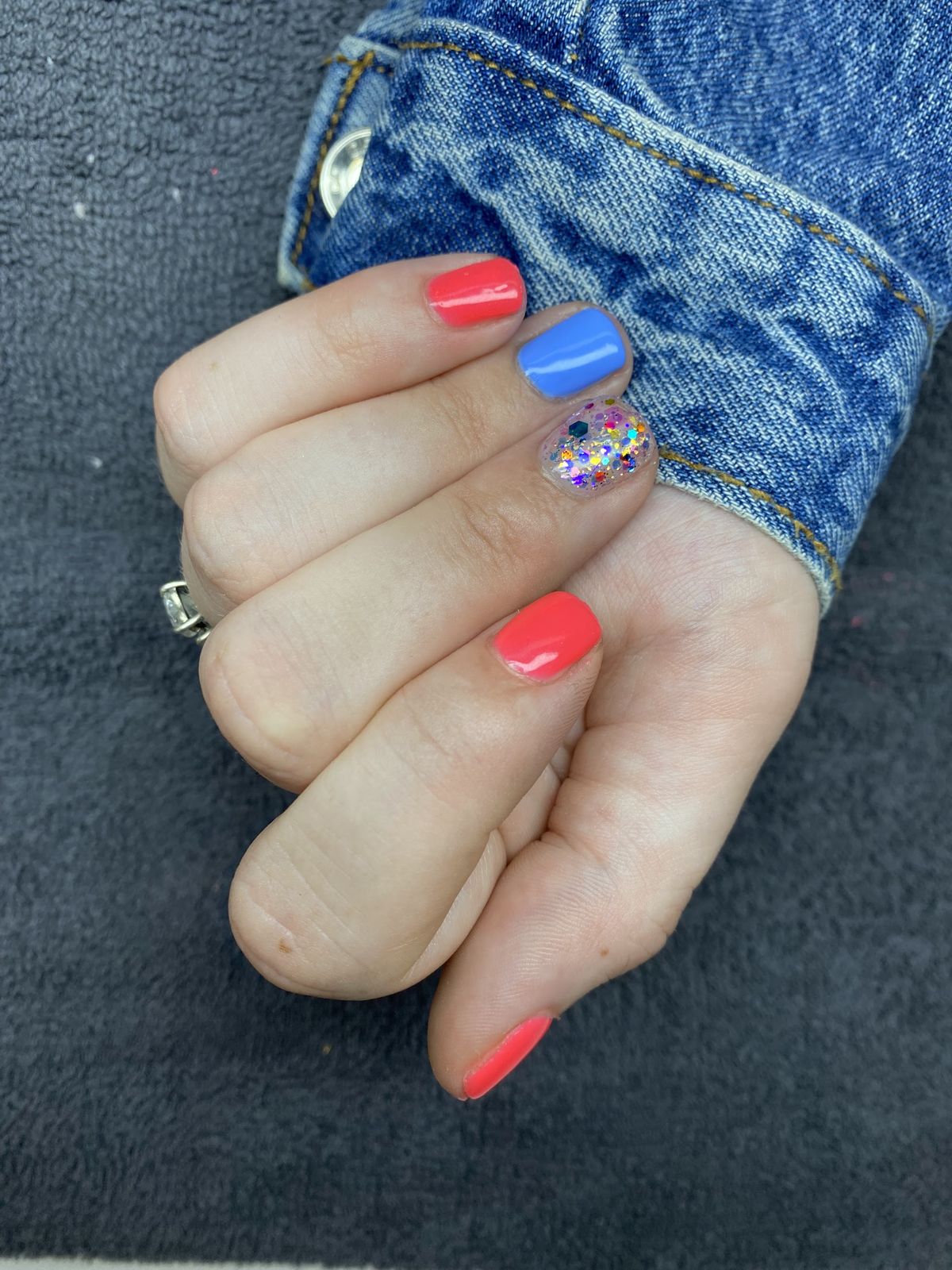 Koraalrode nagels met een blauwe en een glitter accentnagel