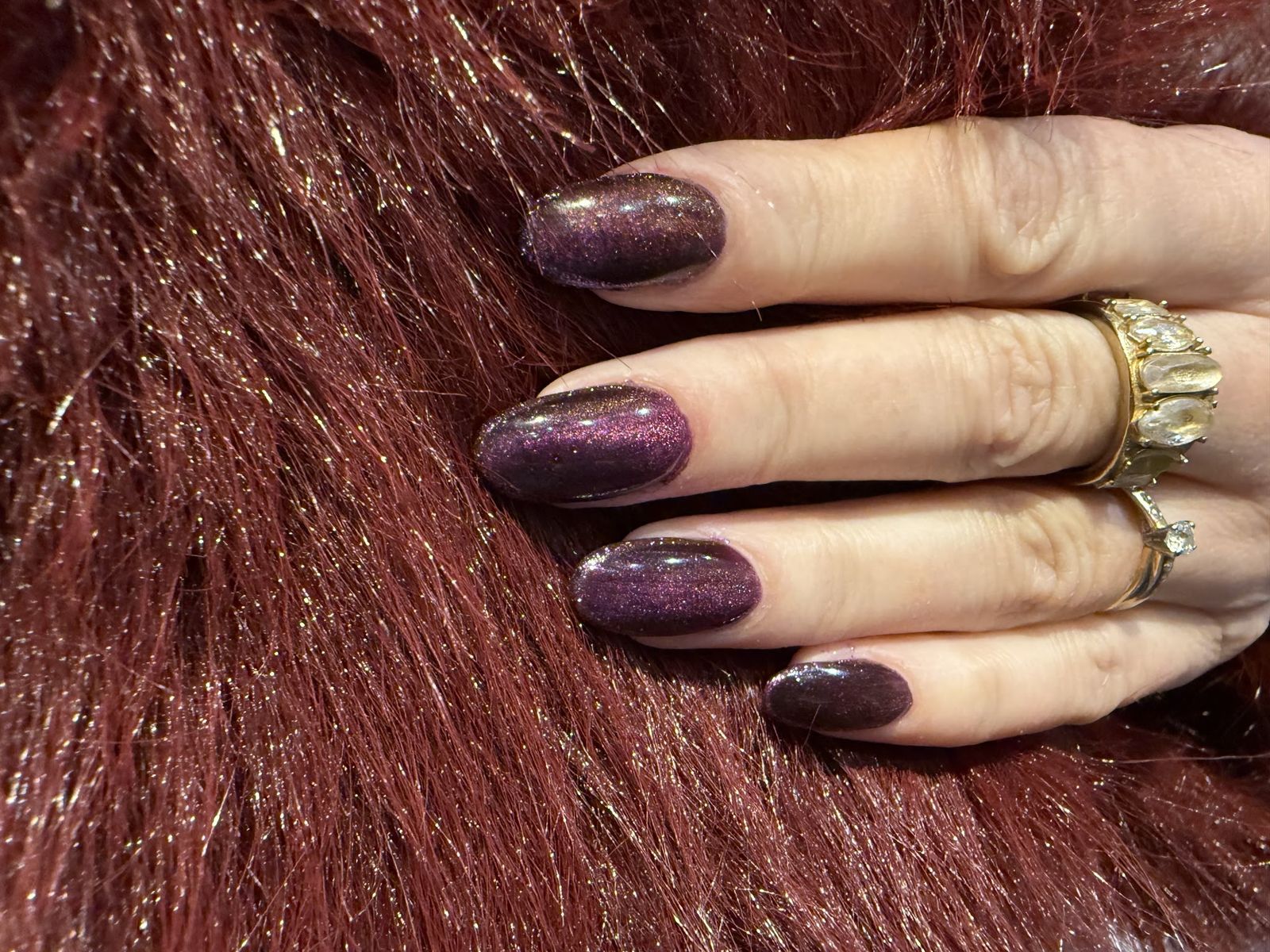Donkere aubergine glitternagels op rood bont, gezet in de nailboutique